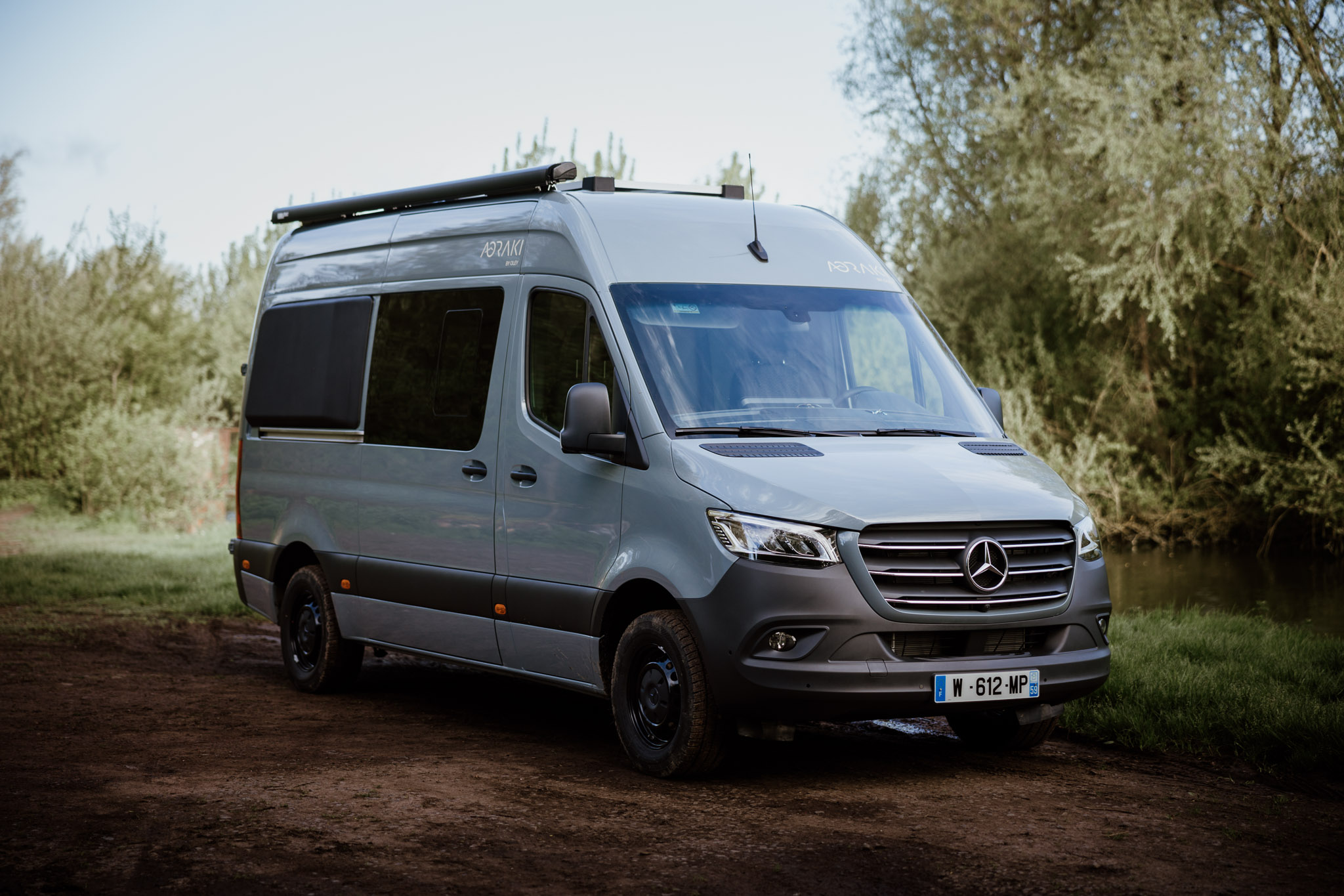 Vue 3/4 du Mercedes Sprinter L2H2 Aoraki, fourgon aménagé sur mesure pour deux personnes par OLEY WORKSHOP – design épuré, finitions haut de gamme et allure d’aventure.