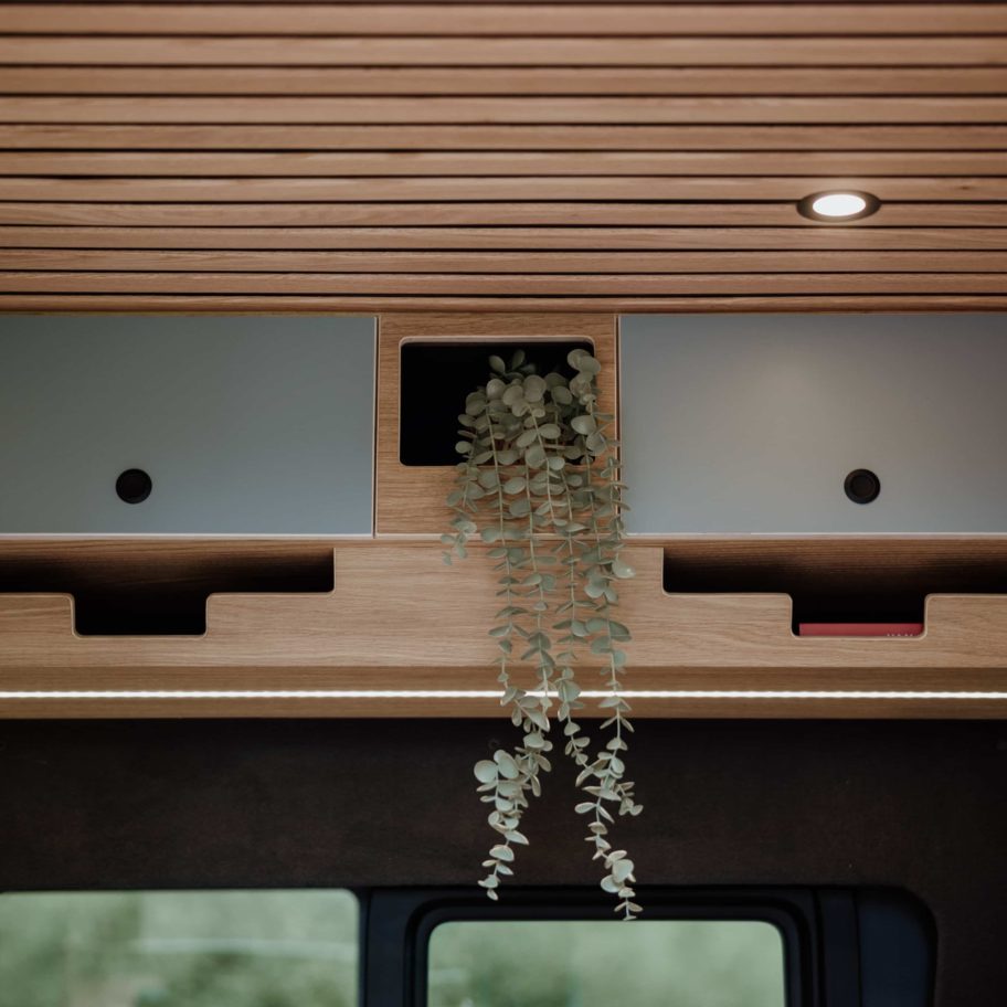 Meuble haut du Mercedes Sprinter Aoraki – finition bois et façade gris mat avec éclairage LED intégré.