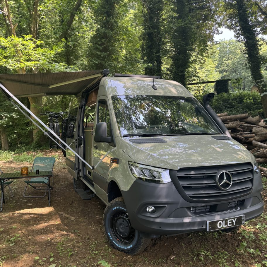 Van aménagé Mercedes Sprinter 4x4 en forêt avec store Fiamma ouvert et installation bivouac