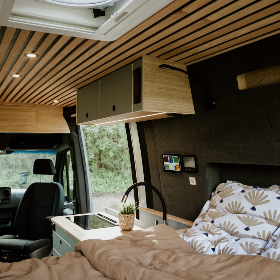 Espace nuit du Mercedes Sprinter Aoraki – lit double confortable, habillage bois et ambiance cocooning.