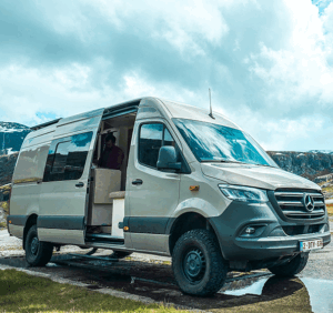 Fourgon Mercedes Sprinter stationné dehors avec la porte latérale ouverte.