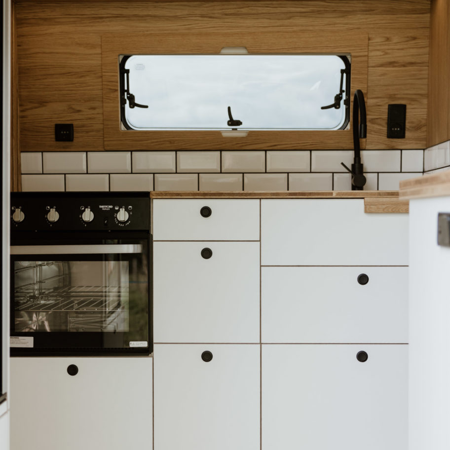 Photo montrant les tiroirs et placards bas de la cuisine du fourgon, avec une finition moderne et épurée.