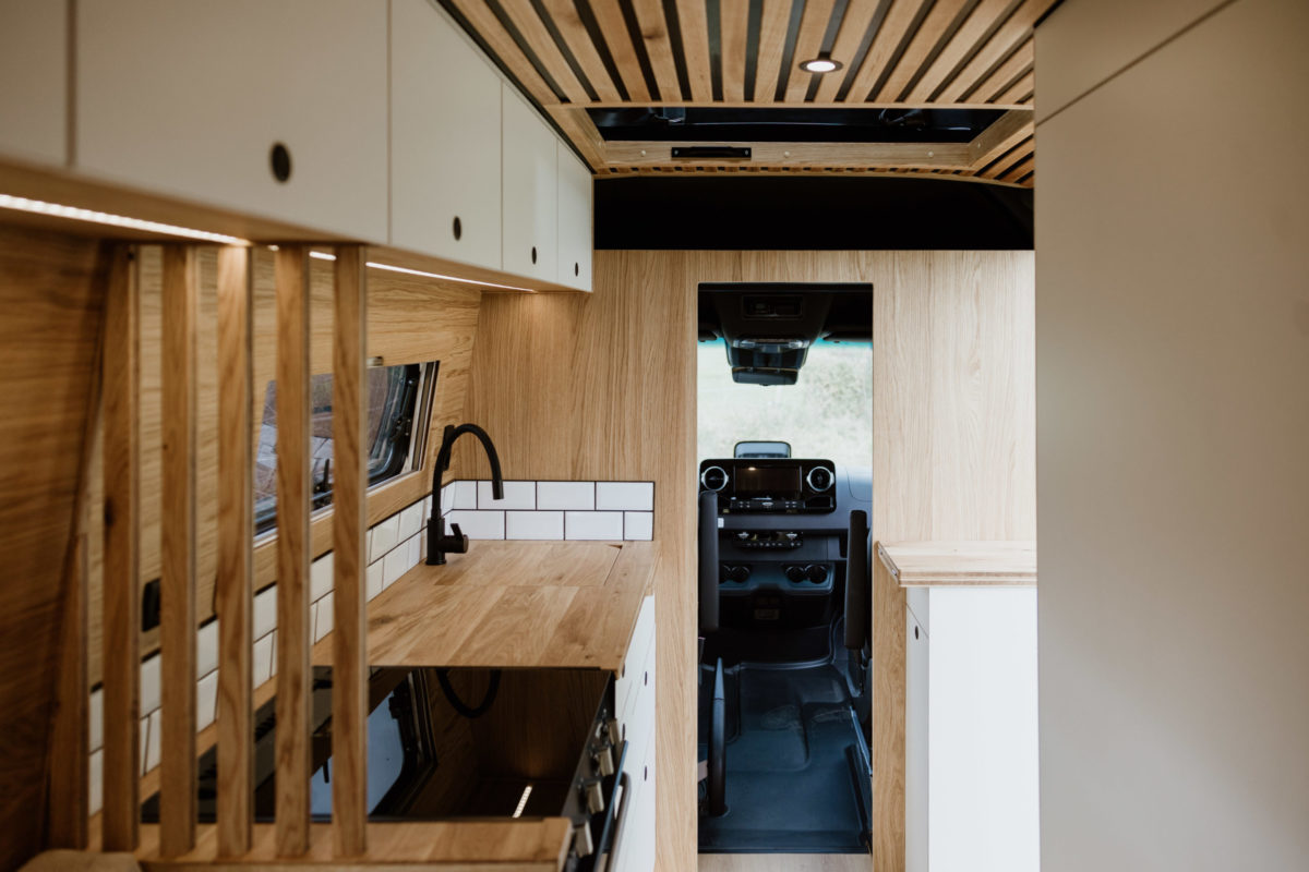 Intérieur du Mercedes Sprinter 4x4 L4H2 519 CDI “Signature” aménagé par OLEY WORKSHOP – cuisine sur mesure en chêne et blanc mat, design épuré et finitions haut de gamme.