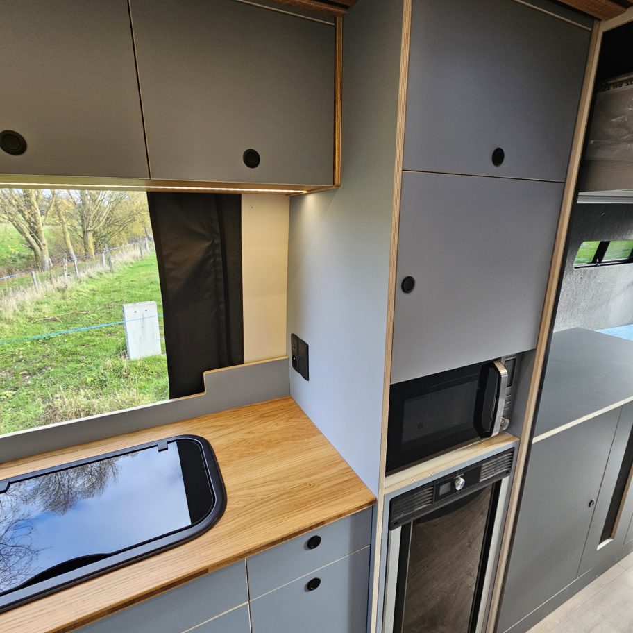 Bloc cuisine avec plan de cuisson, rangements et finition bois.