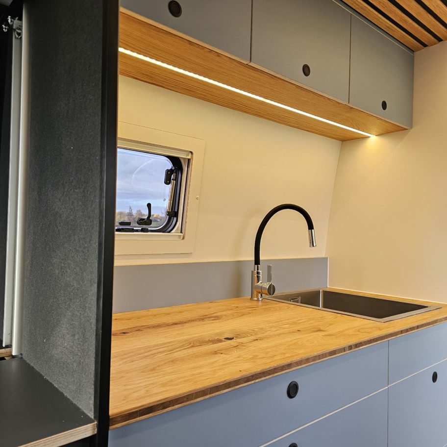 Espace cuisine avec évier, plan de travail bois et éclairage LED.