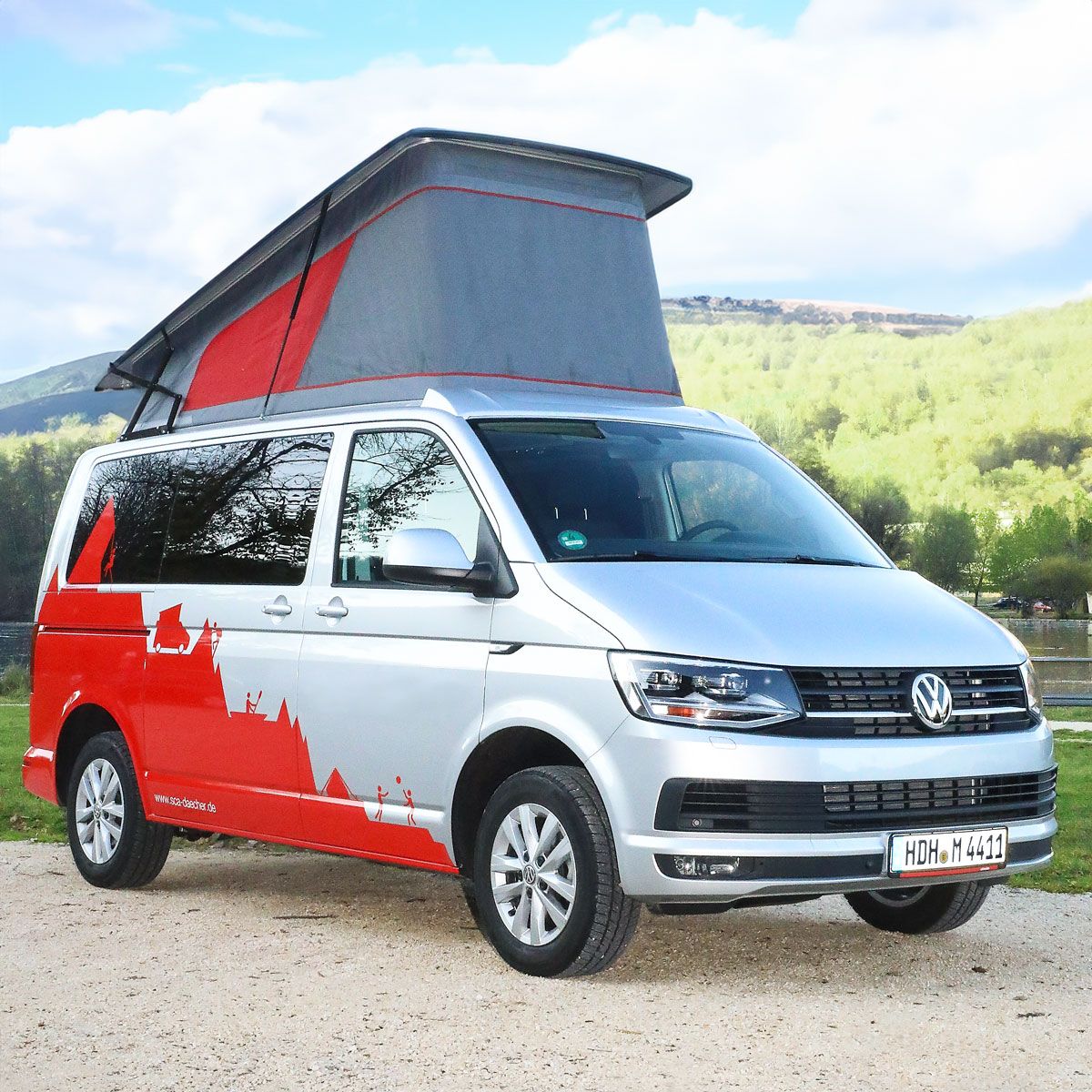 Van aménagé blanc et rouge avec toit relevable SCA 290/292, garé en pleine nature.