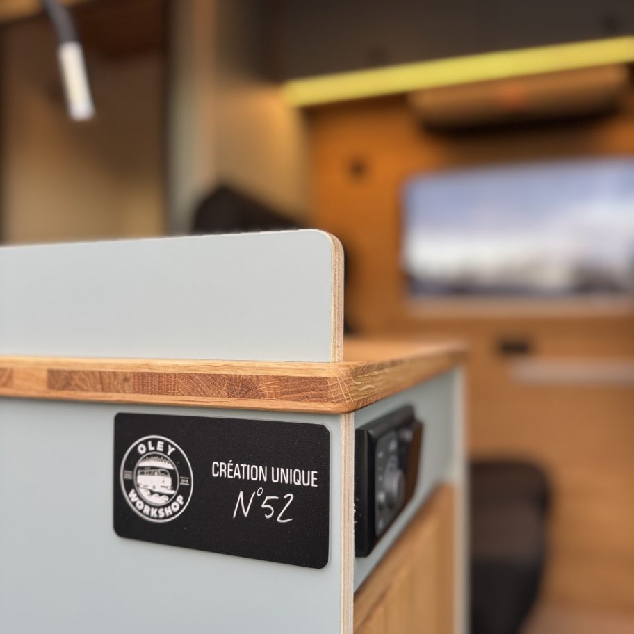 Intérieur d’un van Mercedes Sprinter aménagé avec kitchenette compacte, évier, rangements en bois et siège passager.