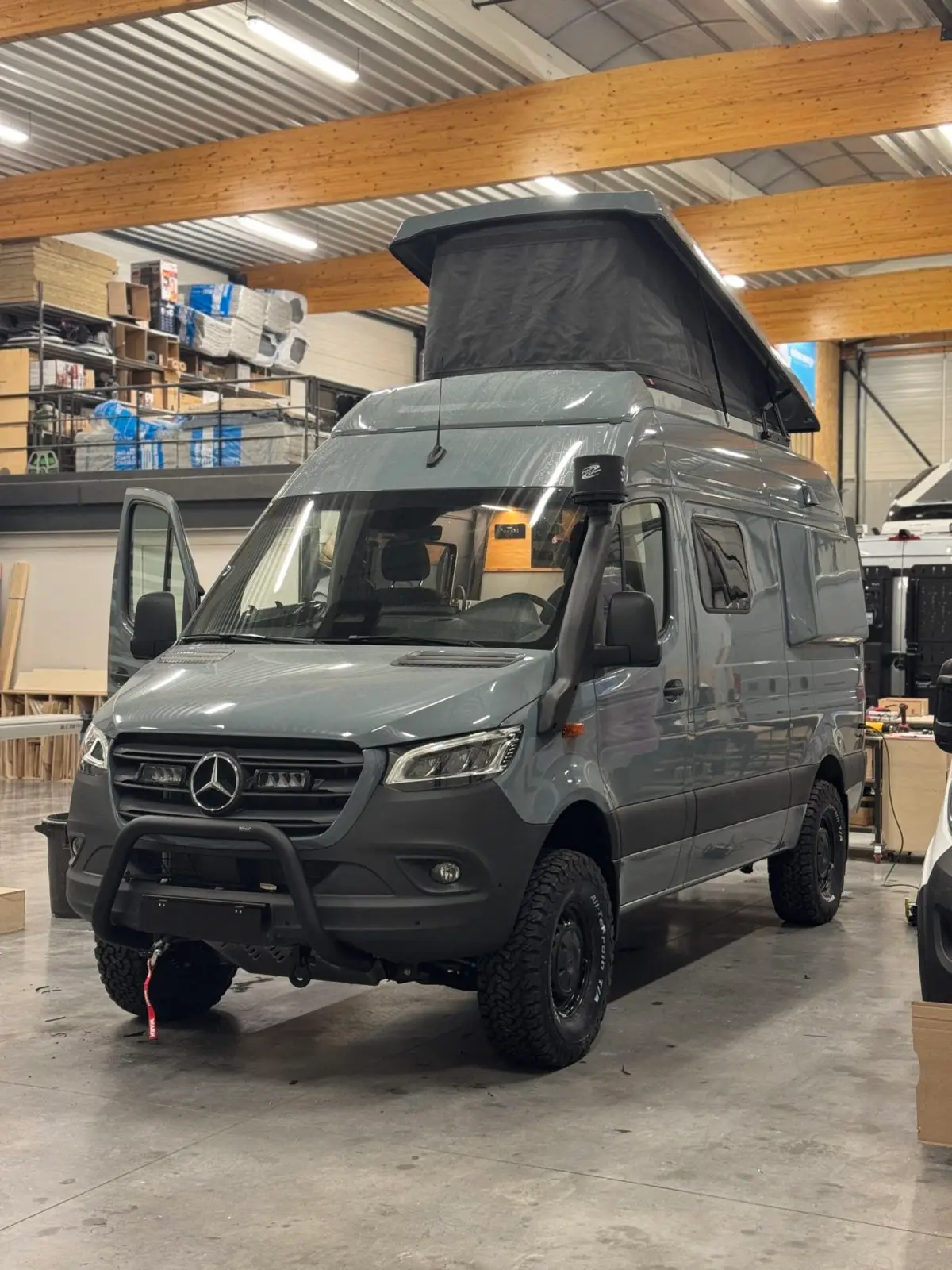 Fourgon Mercedes Sprinter 4x4 avec toit relevable ouvert dans l'atelier de fabrication Oley Workshop