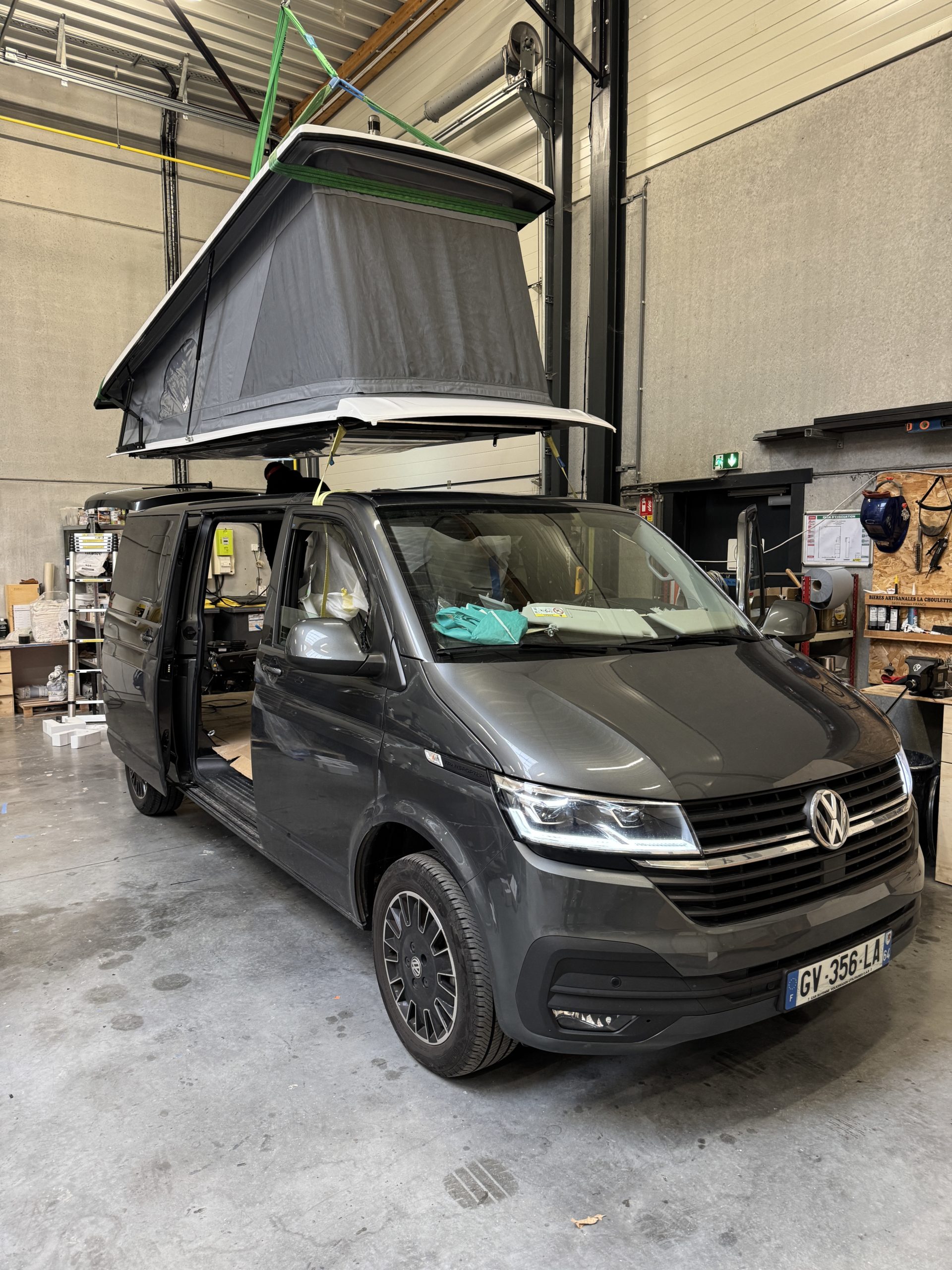 Toit relevable en cours d'installation au-dessus d'un van Volkswagen dans l'atelier Oley Workshop à Roncq
