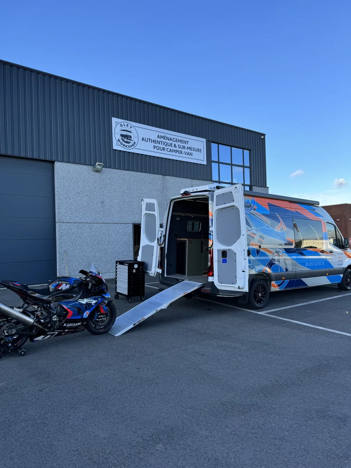 Chargement d'une moto par la rampe du fourgon moto aménagé MotoLab, devant l'atelier Oley Workshop à Roncq près de Lille