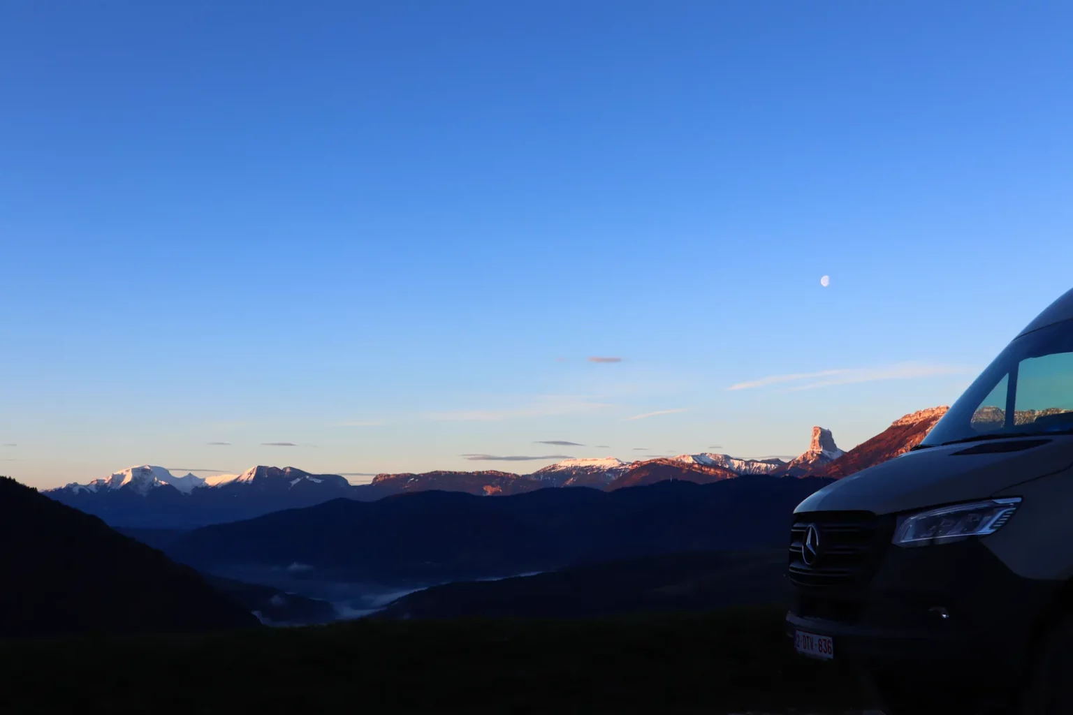 Van aménagé Oley Workshop face à un panorama de montagnes au coucher du soleil, carnet de voyage 50 jours en France