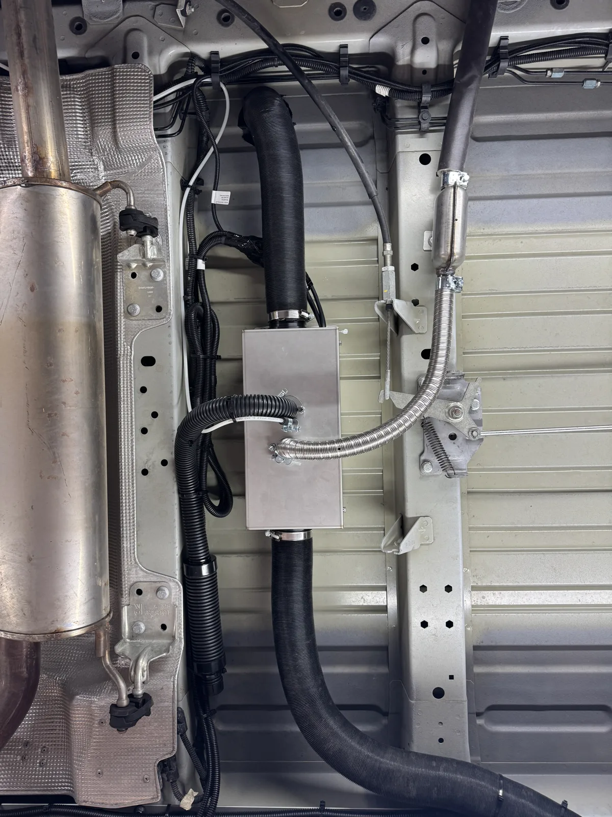 Caisson de chauffage diesel monté sous le châssis d'un fourgon aménagé, avec gaine d'air chaud et échappement inox